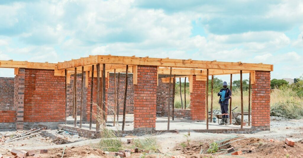 A construction worker in a blue uniform standing inside a brick building frame